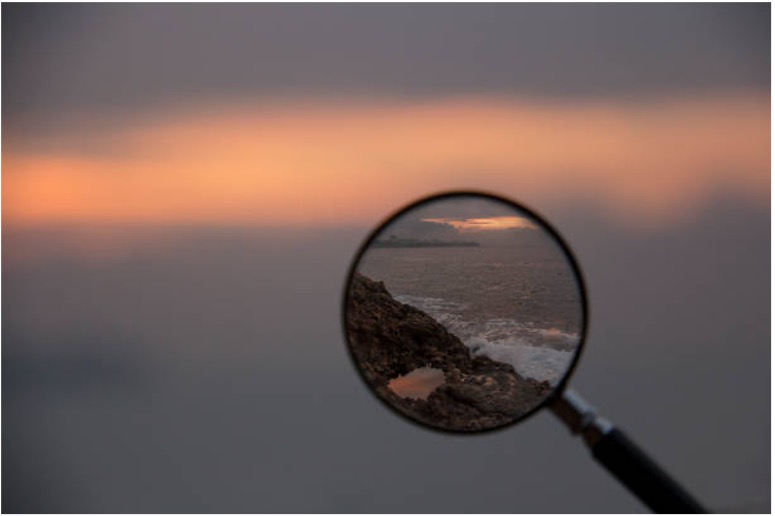 Magnifying glass on coastline at sunset